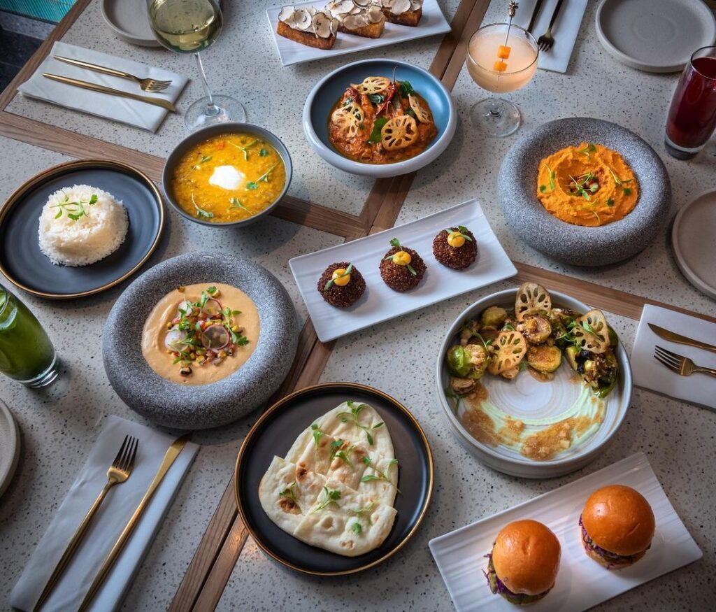 A flatlay of a bunch of vegetarian dishes from VEDA of Ovolo Hotels in Central, Hong Kong on a dinning table.