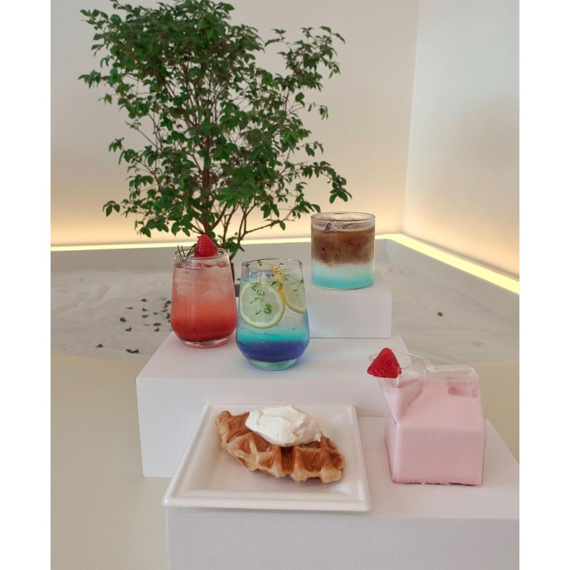 The image is at Milk Bar cafe, in Sham Shui Po (Hong Kong). There is a blue latte, summer blue soda, iced strawberry ade, strawberry milk and a cream butter croffle.